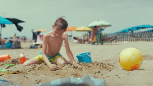 Child Digging in Sand on Sunny Beach Day
