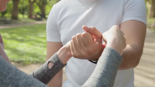 Woman Helps Man With Fitness Tracker in Park