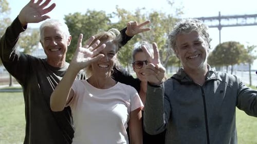 Group of Smiling Friends Waving in Urban Park
