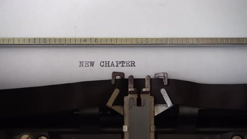 Typing phrase NEW CHAPTER on retro typewriter. Close up.