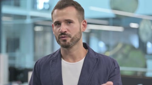 Bearded Man Speaking to Camera in Office Setting