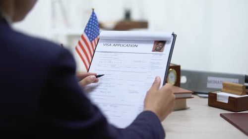 Female Immigration Inspector Denying Visa Application, American Flag on Table