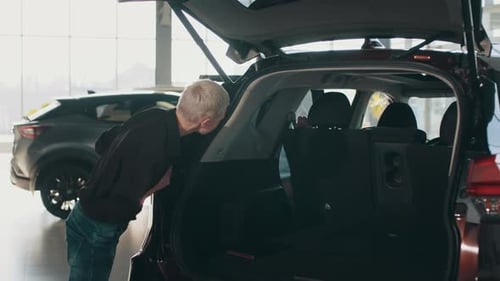 Car Salesman Showing Customer Car in Automotive Dealership Showroom