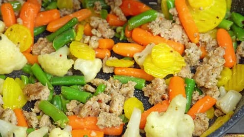 Nahaufnahme von dampfender Bratpfanne und gemischtem Gemüse mit Hackfleisch.