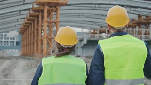 Rear View of Construction Workers Talking and Walking
