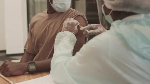 Adult Receives Vaccine from Medical Professional Indoors