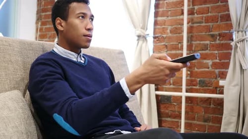 Young Man Watching TV on Couch, Relaxing at Home