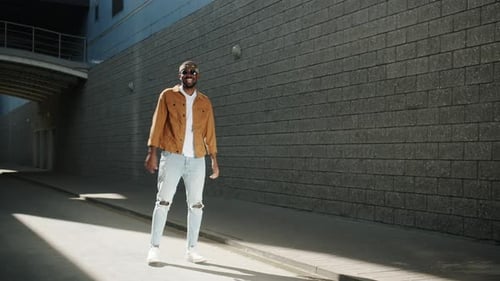 Homem afro-americano despreocupado pulando e rindo, aproveitando o tempo de lazer ao ar livre