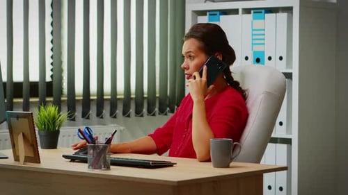 Woman Talking on Cell Phone at Her Desk