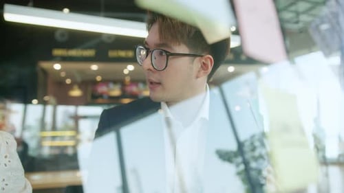 Intelligenter attraktiver positiver asiatischer Geschäftsmann mit Brille arbeitet aus der Ferne