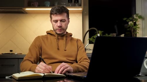 Man Works Using Laptop at Home Workplace Reading Paper Documents