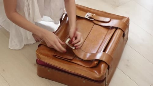 Woman Opens Vintage Leather Suitcase at Home