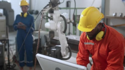 Technischer Ingenieur verwaltet die Tastatureingabe, programmiert die Bewegung des modernen Schweißroboterarms