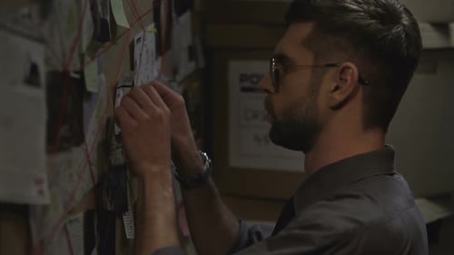 Man Investigates Crime Board with Evidence