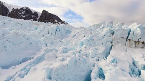 Large glacier on sea with snowy mountain, panning drone shot