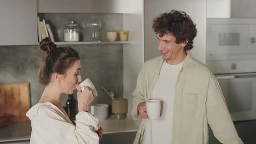 Couple Drinking Coffee and Chatting in Kitchen