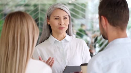Empleados multirraciales y colegas hablando usando una tableta en la oficina