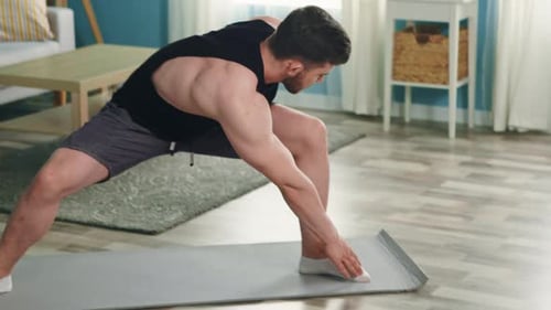 Muscular Man Stretching on Yoga Mat at Home