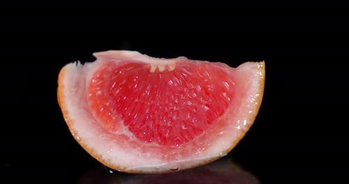 A Piece of Grapefruit Falls Into the Water with Splashes.