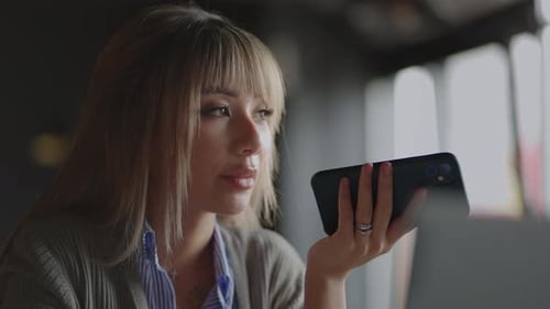 Young Woman Talking into Smartphone Inside