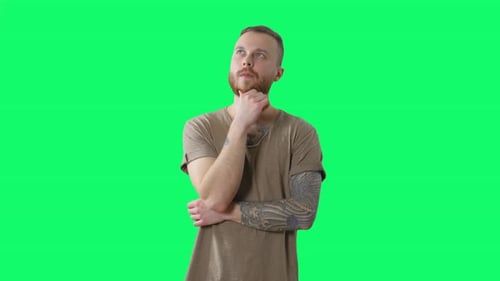 Serious Handsome Man on Chroma Key. Friendly Bearded Tattooed Hipster Is Thinking and Doubting on