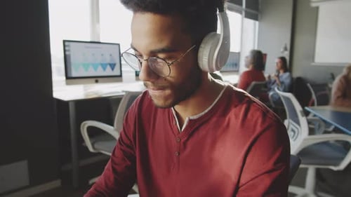 Young Man in Headphones Typing on Laptop during Office Workday