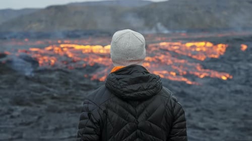 Person Views Flowing Lava in Volcanic Landscape