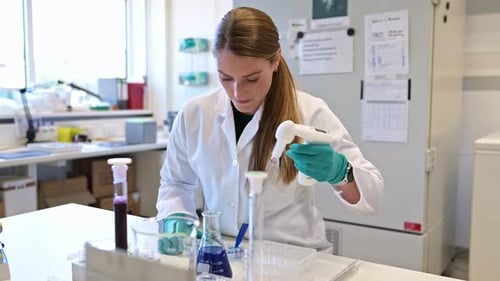 Laboratory assistant pipetting blue liquid
