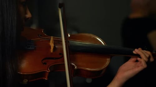 Woman Playing Violin in a Dimly Lit Room