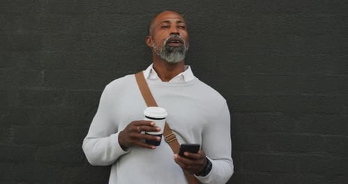 Man On Phone With Coffee Against Dark Wall