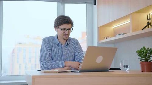 Man works remotely with colleagues at work through a laptop using video communication.
