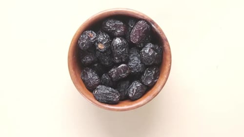 Slow Motion of Fresh Date Fruit Falling in a Bowl on Table