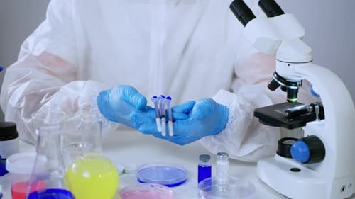 Medical Researcher Holds Three Blue Liquid Syringes