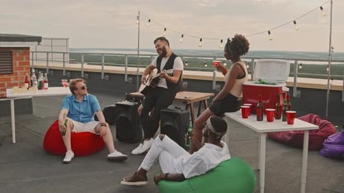 Friends Enjoying Rooftop Party with Guitar Music