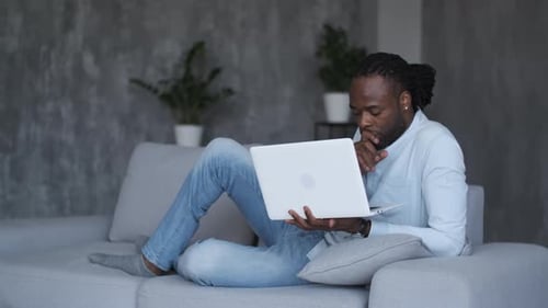 Man Using Laptop Relaxing on Couch at Home