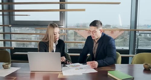 Man and a Woman Discussing Work in the Brightly Lit Modern Office. Concerned Male and Female Working
