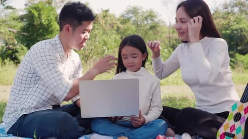 Family Enjoys Laptop Together at Sunny Park Picnic