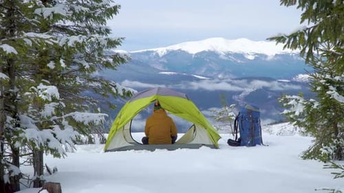 Tourist Relaxes in a Tent in the Mountains in Winter