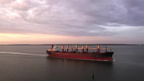 Cargo Ship Sailing on Ocean at Sunset