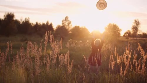 Woman Tossing Hat in a Golden Field