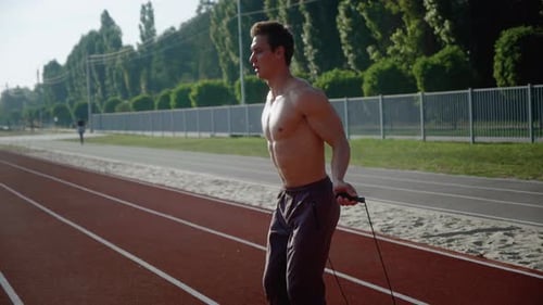 Muscular Man Skipping Rope on Running Track