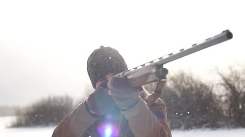Man Aims Rifle in Snowy Winter Field