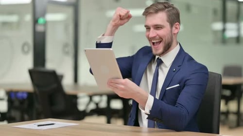 Excited Businessman Celebrates Success with Tablet in Office