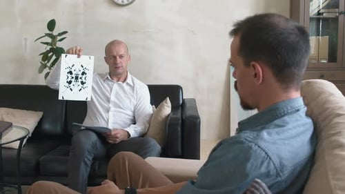 Psicoanalista masculino que muestra la prueba de Rorschach a un cliente