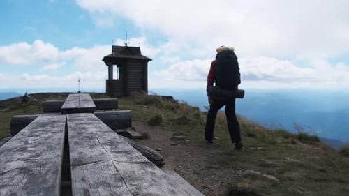 Tourist with Backpack on the Top of Mountain Spreads His Arms To the Sides