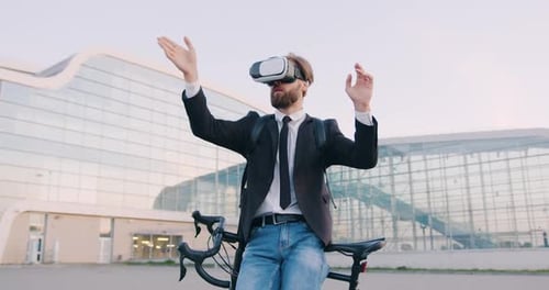 Homme en tenue professionnelle qui s'appuie sur son vélo et travaille dans un casque de réalité virtuelle