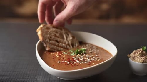 Chefs Hand Serving the Soup with Crispy Toast