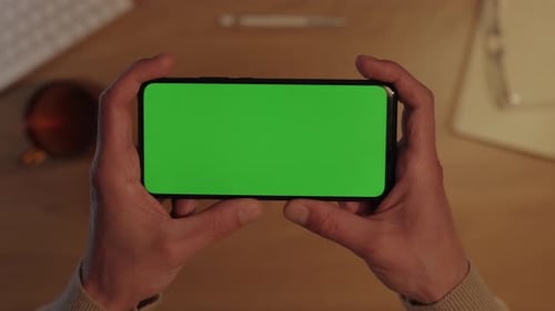 Male Hands Holding Smartphone with Green Mockup Screen
