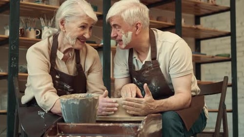 Couple making pottery on wheel in studio