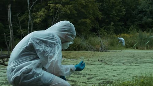 Chemist in Ppe Looking at Flask with Solution Water Analysis From Swamp Wearing Protective Suit and